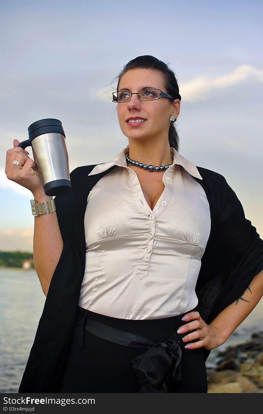 Girl in glasses with coffee stands against the sea