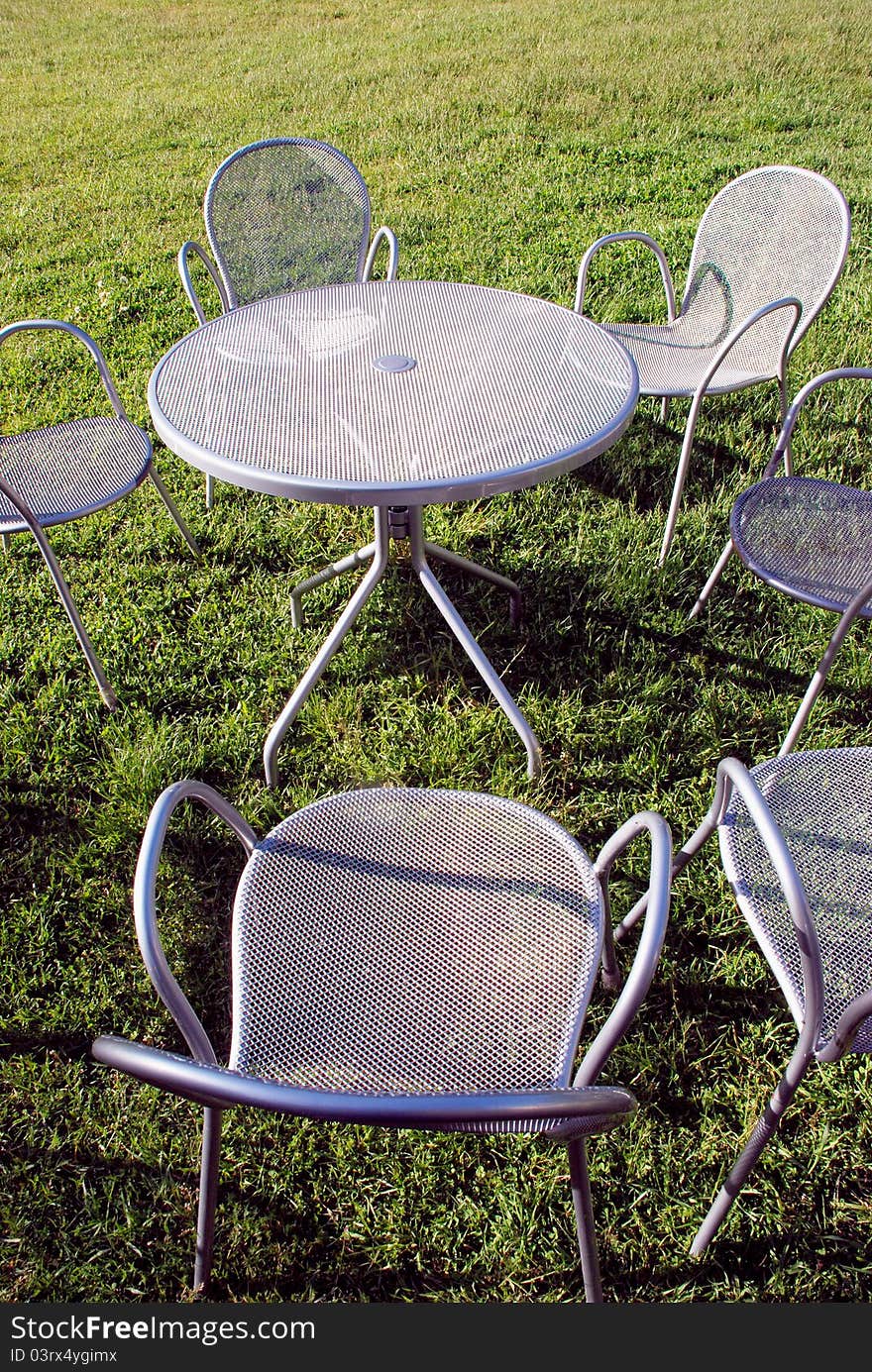 Metal chairs and table on the park grass