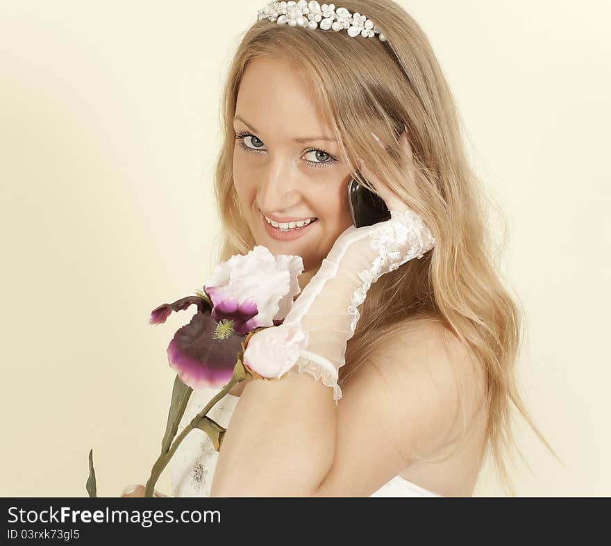 Girl in a wedding dress and an orchid on  cell phone call. Girl in a wedding dress and an orchid on  cell phone call