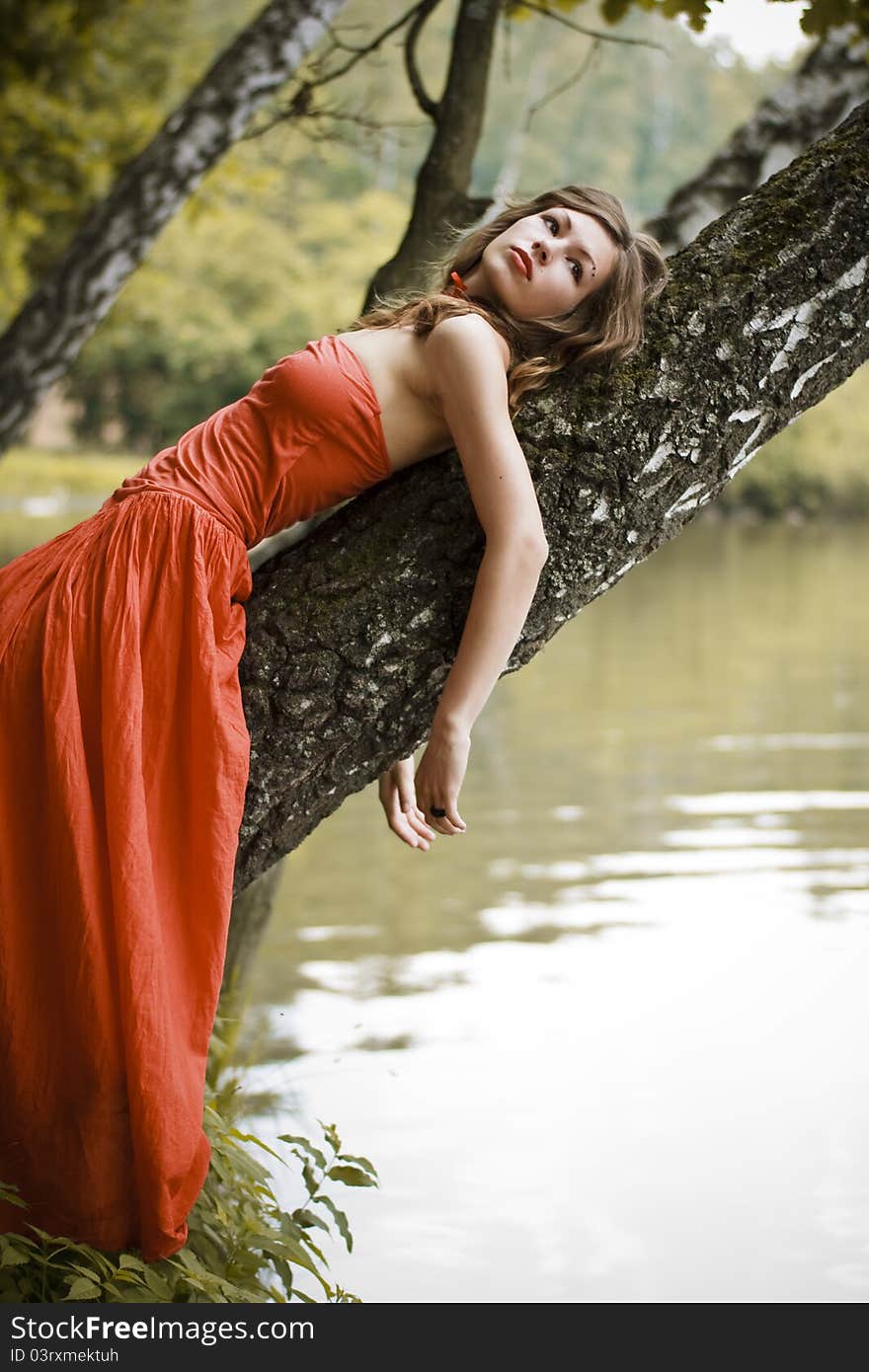 Young woman staying on the bank of the lake. She looks at the sky. Young woman staying on the bank of the lake. She looks at the sky.