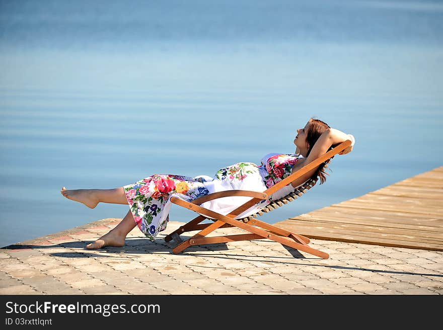 Woman sitting in lounge chair. summer's day on lakeside. Woman sitting in lounge chair. summer's day on lakeside