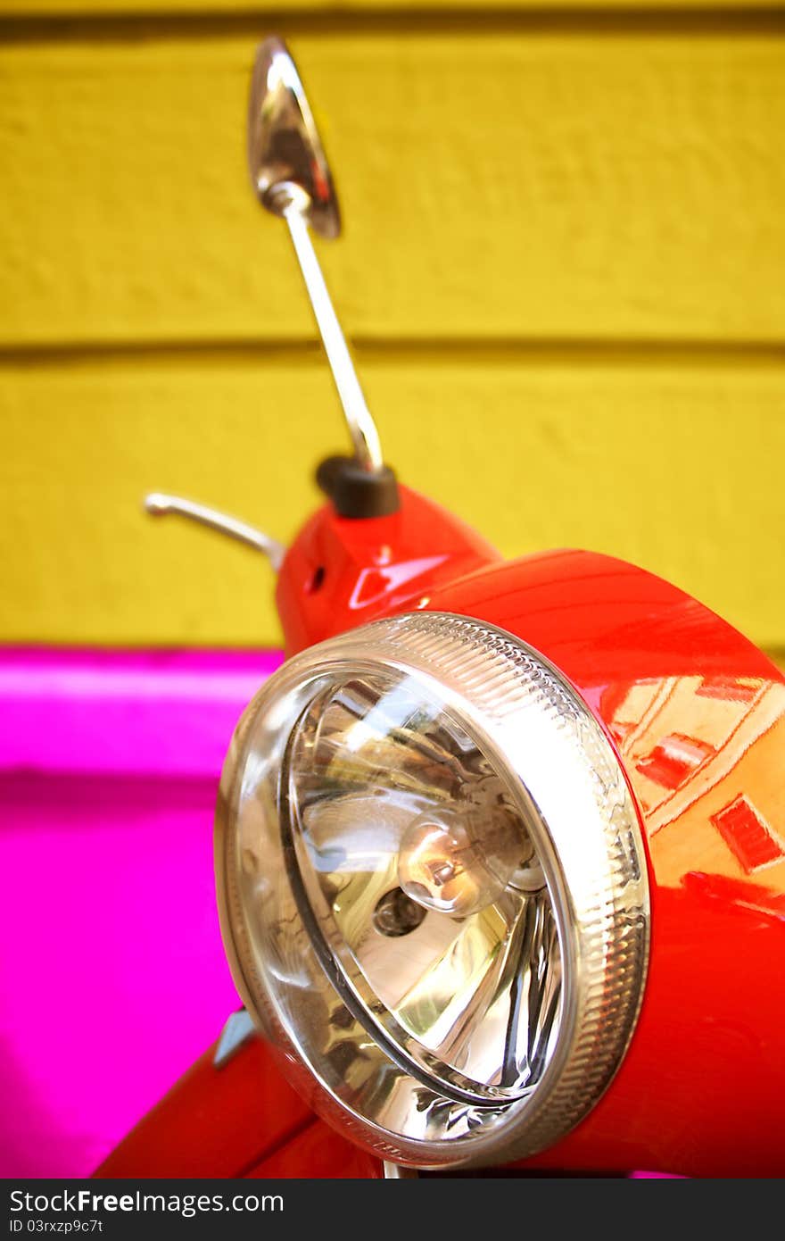 Detail of red moped with rearview mirror and headlight