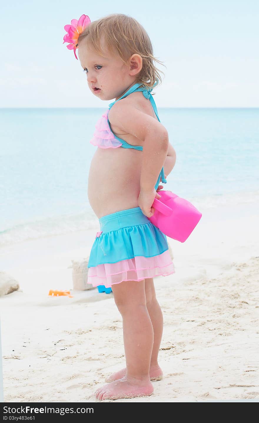 A baby girl is on the beach in the swimming suit. A baby girl is on the beach in the swimming suit