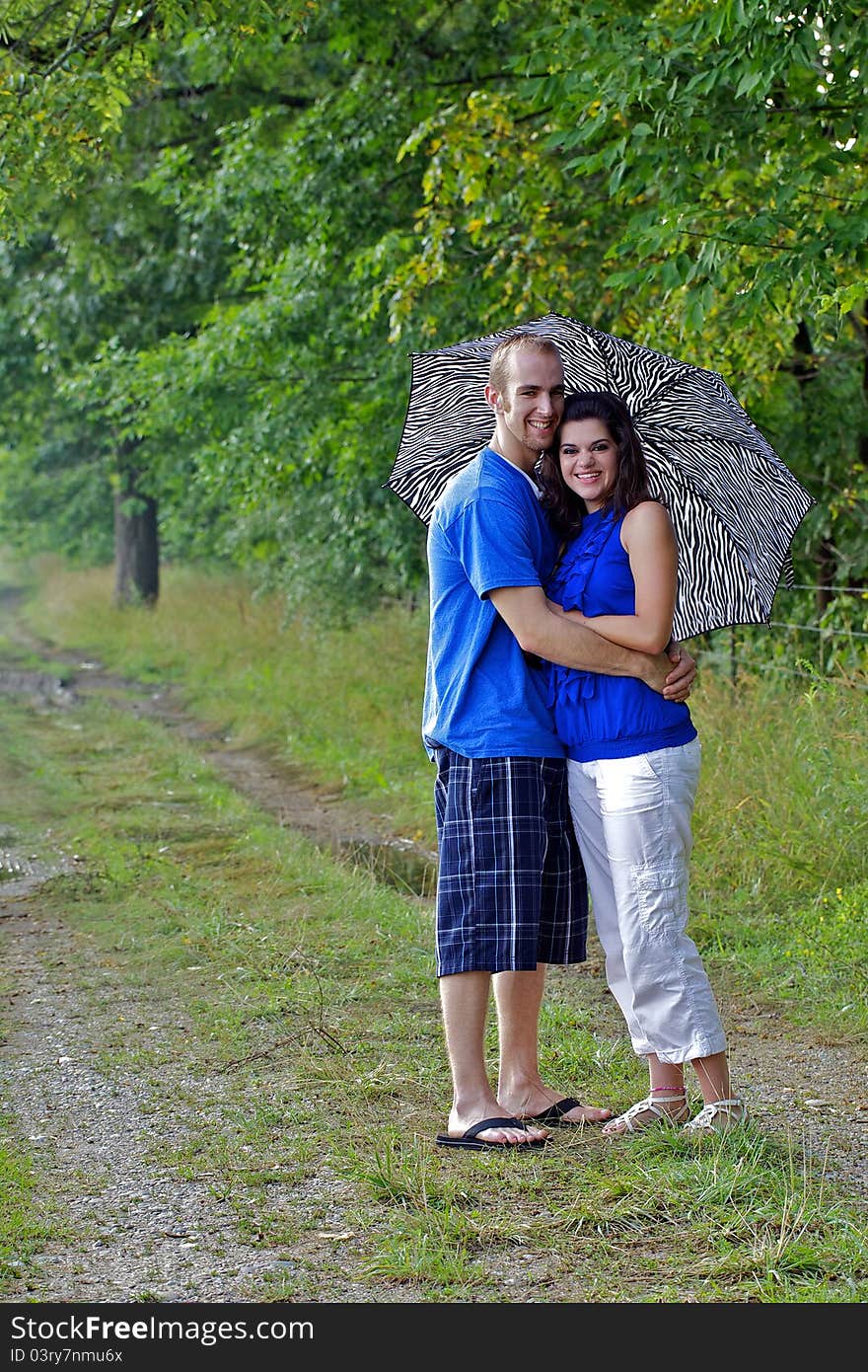 Couple in farm field with arms around each other holding an umbrella. Couple in farm field with arms around each other holding an umbrella