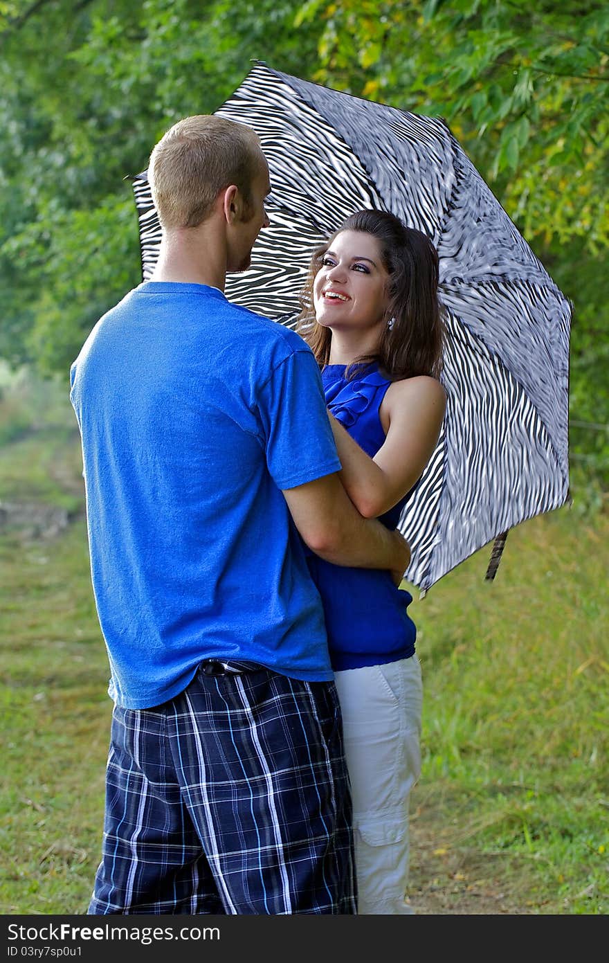 Couple in farm field with arms around each other holding an umbrella. Couple in farm field with arms around each other holding an umbrella