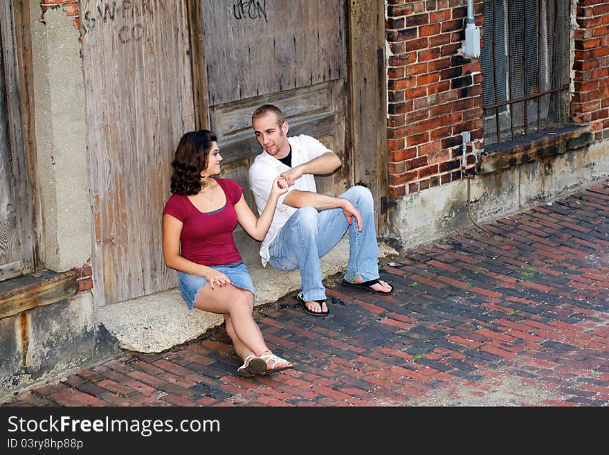 Couple sitting in front of old building enjoying each others company. Couple sitting in front of old building enjoying each others company