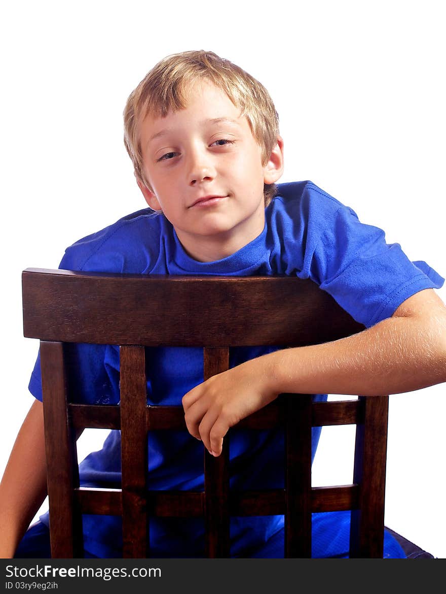 Young boy leaning on a chair with a smirk on his face. Young boy leaning on a chair with a smirk on his face