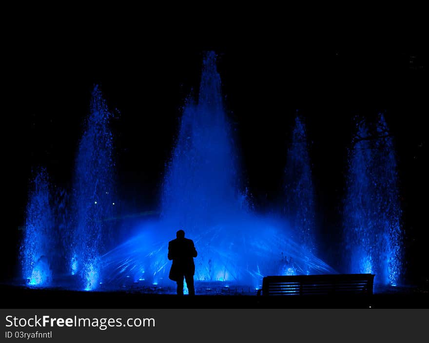 Male standing in front of a beautiful water feature fountain at night. Male standing in front of a beautiful water feature fountain at night