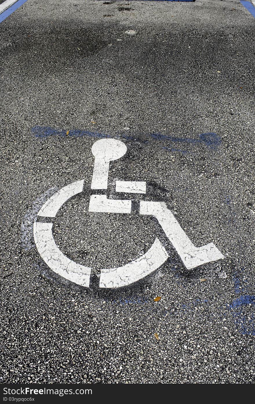 Handicaped parking only space, outside store entrance in a Florida mall, indicated by wheelchair logo painted on the asphalt pavement. Handicaped parking only space, outside store entrance in a Florida mall, indicated by wheelchair logo painted on the asphalt pavement.