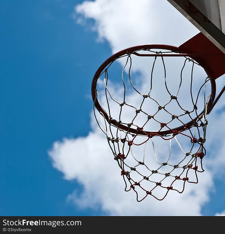 Basketball basket against pines and blue sky.