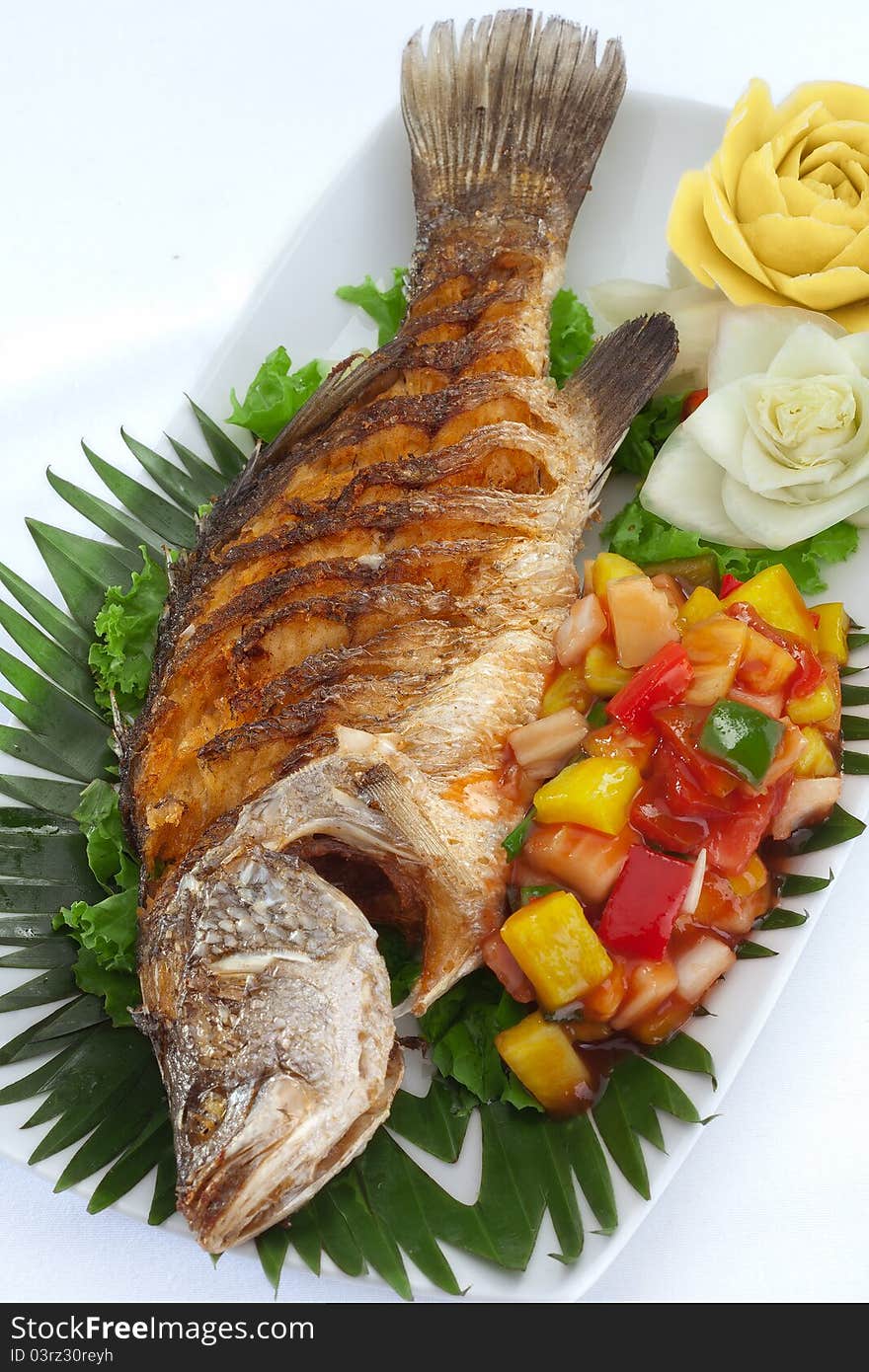 Close up view of nice fried fish with vegetables on white back