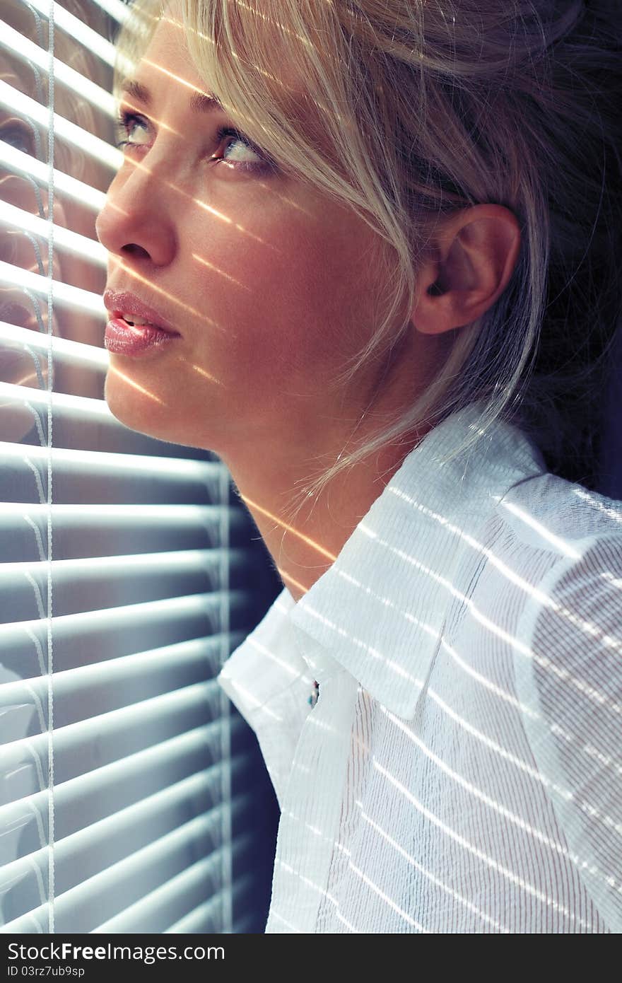 Blonde woman in the sunlight through jalousie