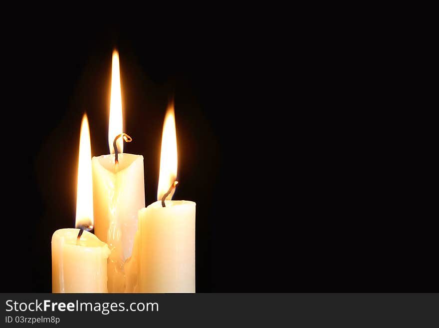 Three ordinary lighting candles on black background with free space for your text