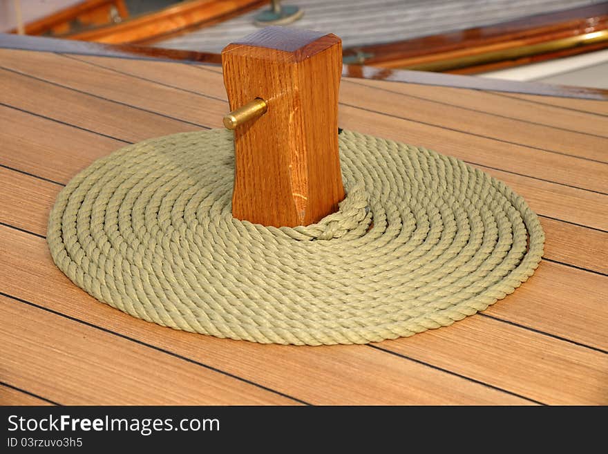 Coiled rope on teak deck. Decorative coiling is called 'cheesing' or 'flemish coil' and was used to help rope dry.