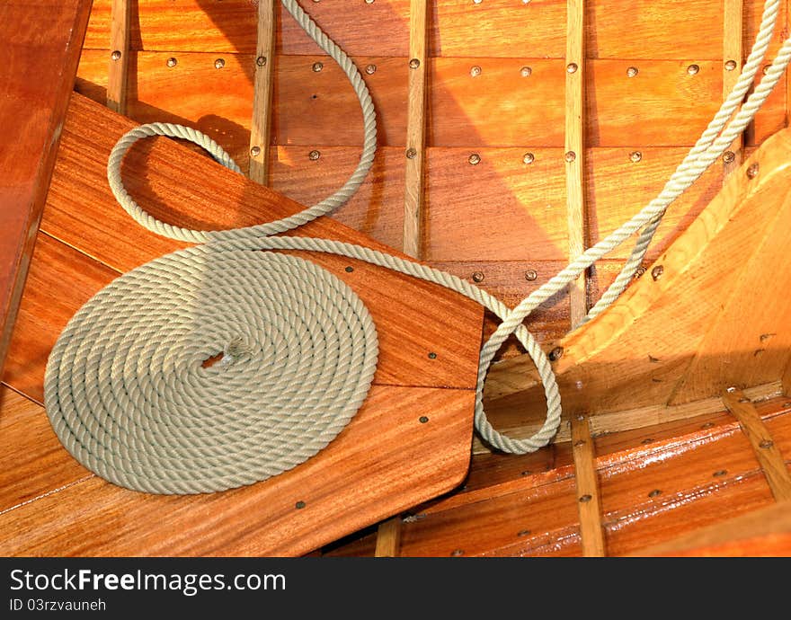 Coiled rope on teak deck. Decorative coiling is called 'cheesing' or 'flemish coil' and was used to help rope dry. Coiled rope on teak deck. Decorative coiling is called 'cheesing' or 'flemish coil' and was used to help rope dry.