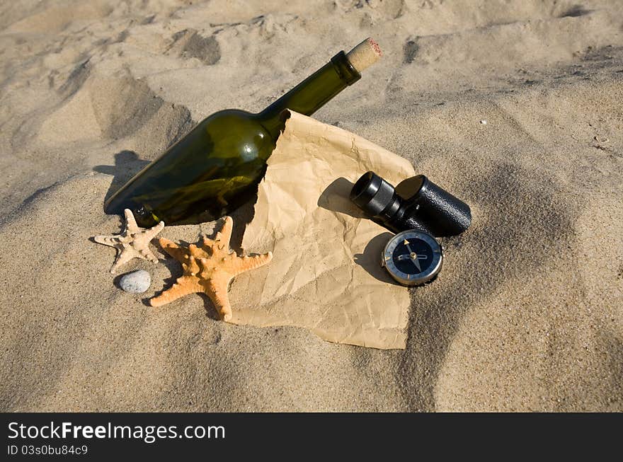 Old paper, the compass, a sink and a bottle on sand background. Old paper, the compass, a sink and a bottle on sand background