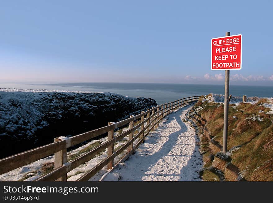 Warning sign on a winter snow cliff walk