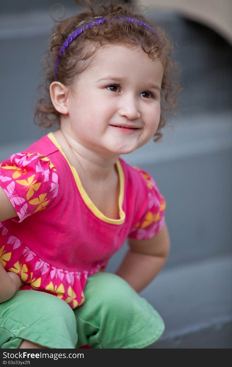 Little girl sitting on the stairs with cute smile. Little girl sitting on the stairs with cute smile.