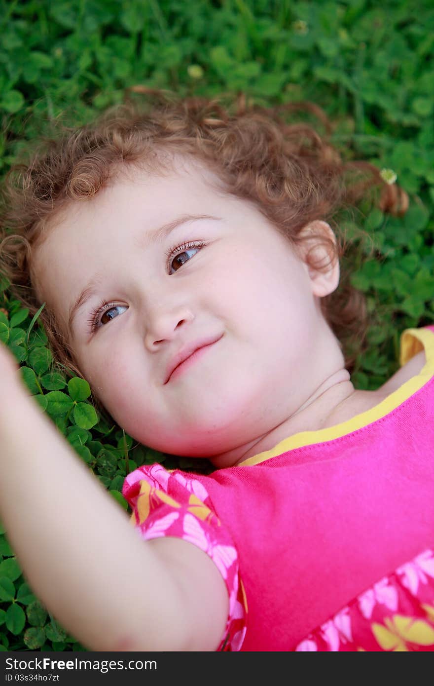 Little adorable girl lying on grass