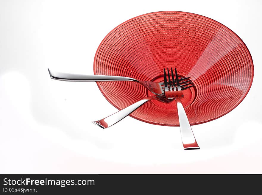 Three metal forks over red plate. Three metal forks over red plate