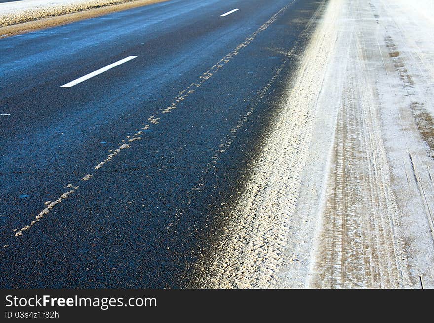 Part of the asphalted road to a winter season (on road traces from passing cars). Part of the asphalted road to a winter season (on road traces from passing cars)