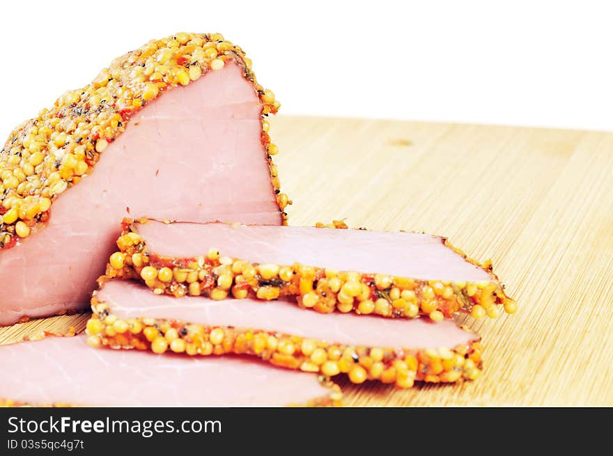 Piece of a ham with spices on a wooden board. Onwhite background.