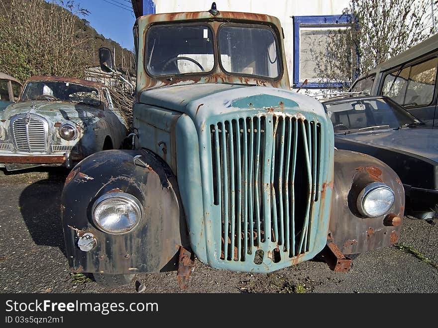 Old truck abandoned and rusting in yard with old abandoned car in background. Old truck abandoned and rusting in yard with old abandoned car in background