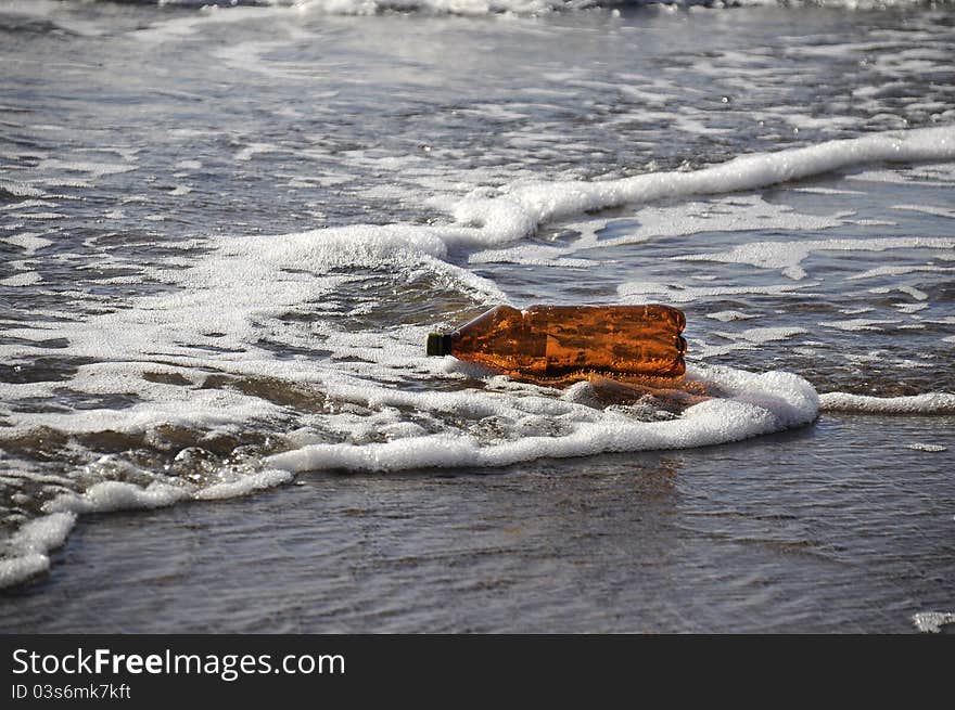 Layjng bottle on seashore in waves. Layjng bottle on seashore in waves