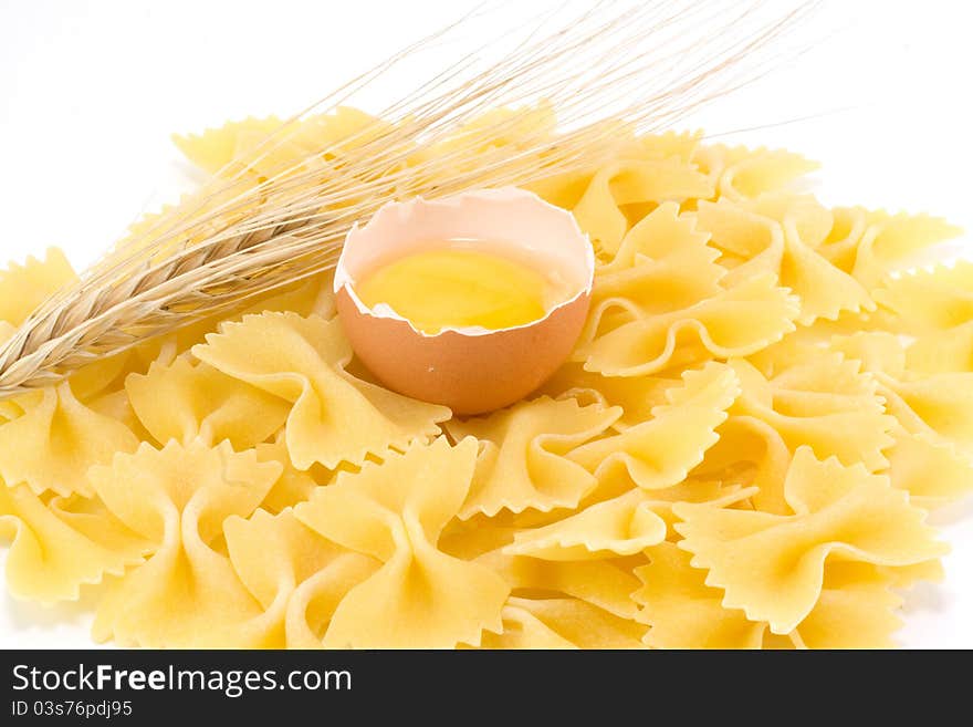 Broken egg, pasta and wheat ears isolated and white background