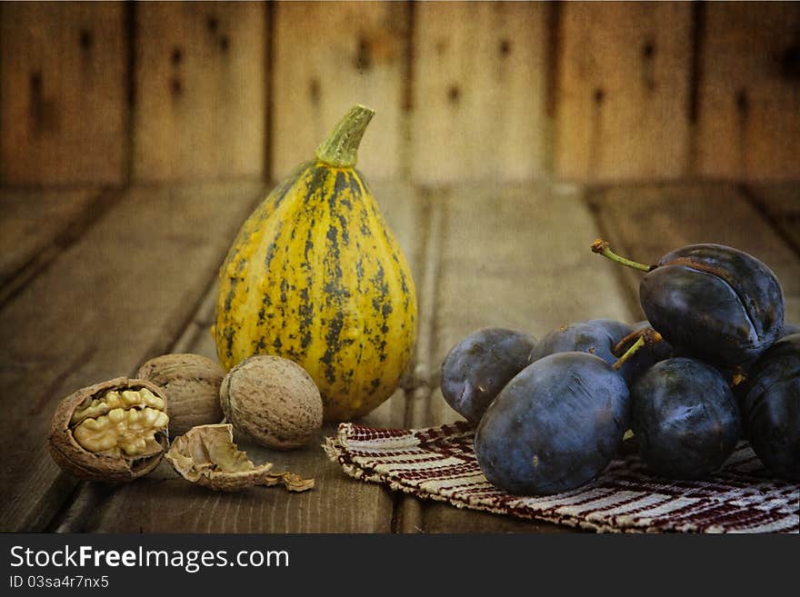 Squash, plums and nuts on an old wood- still life. Squash, plums and nuts on an old wood- still life