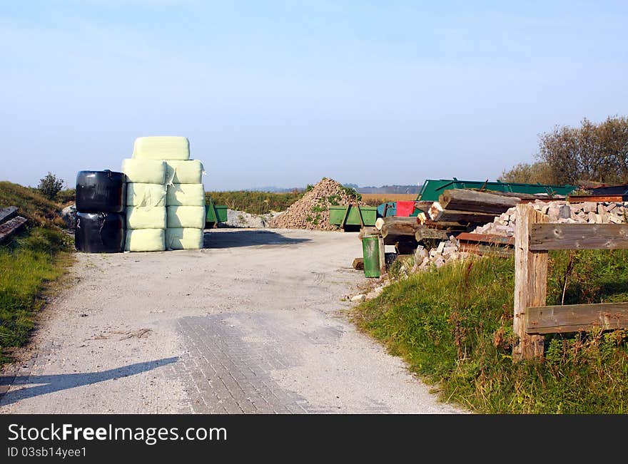 Typical yard in the farm with tools, bricks, manure and hay. Typical yard in the farm with tools, bricks, manure and hay