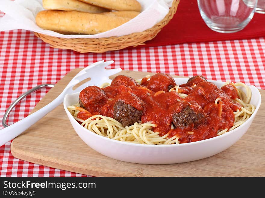 Spaghetti and meat balls in a serving bowl with bread sticks. Spaghetti and meat balls in a serving bowl with bread sticks