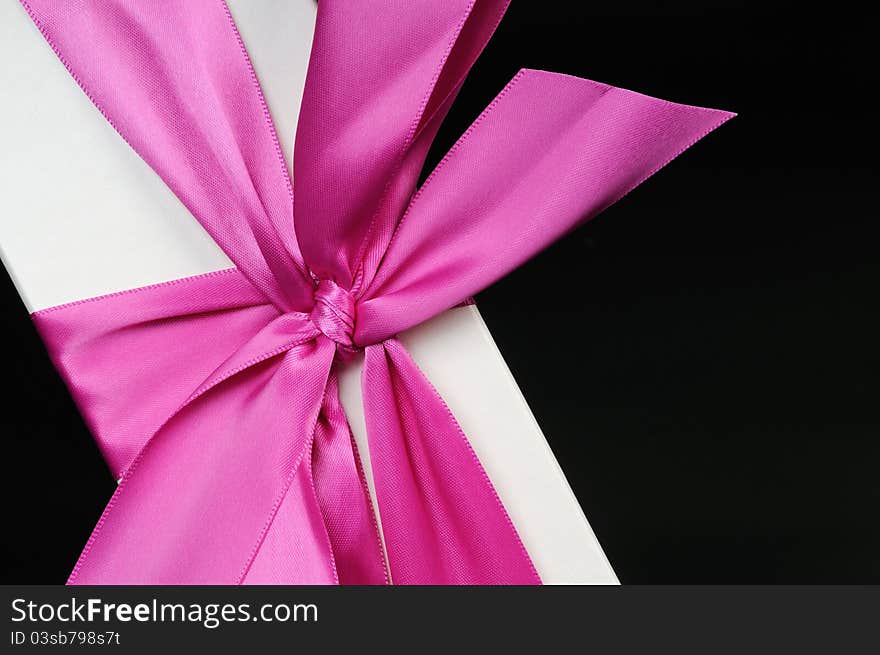 Gift box with a big pink bow close up. On a dark background. Gift box with a big pink bow close up. On a dark background.