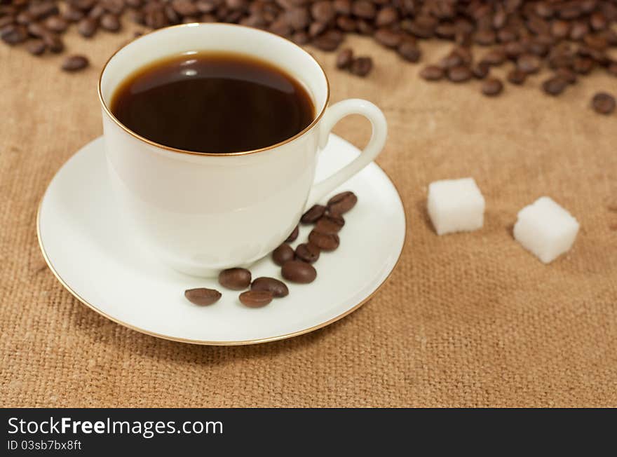 Coffee beans and cup on burlap