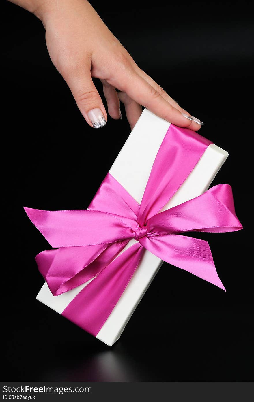 Gift box with a big pink bow and woman's hand. On a dark background. Gift box with a big pink bow and woman's hand. On a dark background.