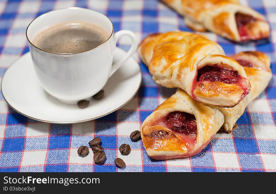 Cherry bun on a plate and cup of coffee