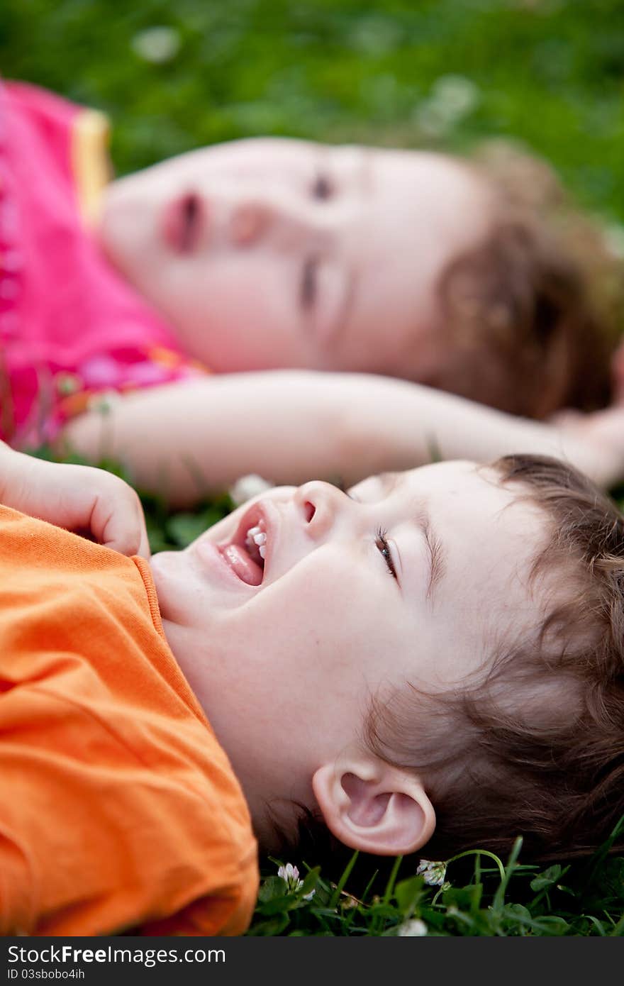 A smiling boy and a little girl are lying on the grass. A smiling boy and a little girl are lying on the grass