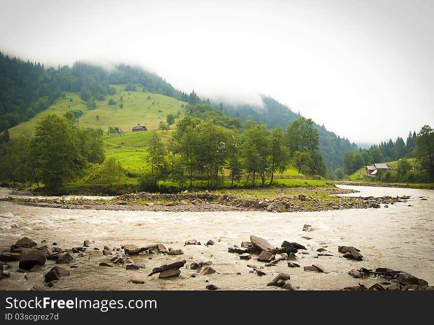 A mountain landscape view on a tiny village with wooden huts and a mountain river in the Ukrainian Carpathian mountains. A mountain landscape view on a tiny village with wooden huts and a mountain river in the Ukrainian Carpathian mountains