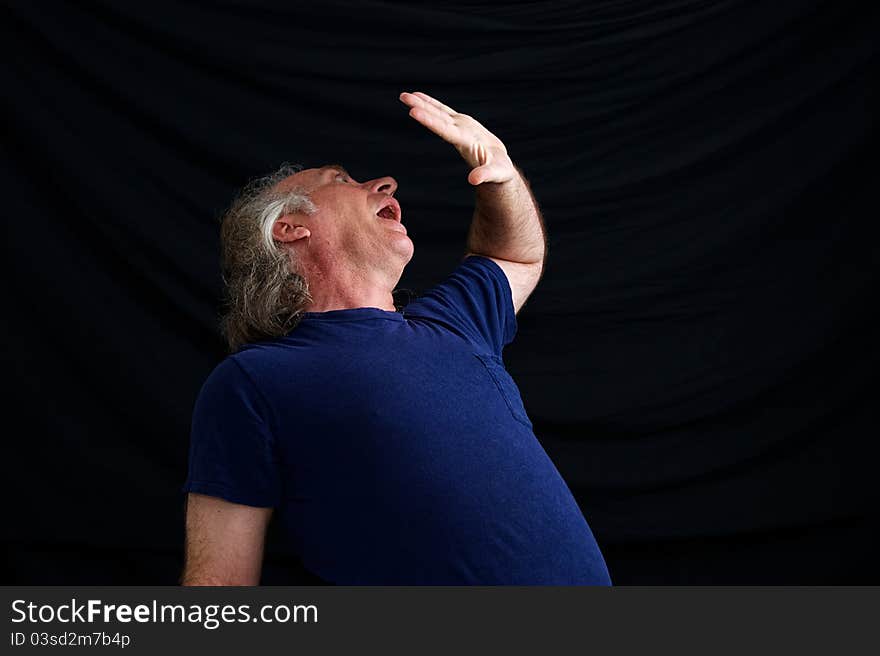 An older white man is cowering in fear and has hand up in front of face to protect him. An older white man is cowering in fear and has hand up in front of face to protect him.