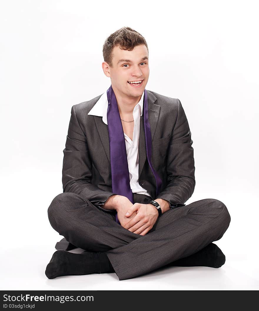 Relaxed young business man sitting on the floor over white background