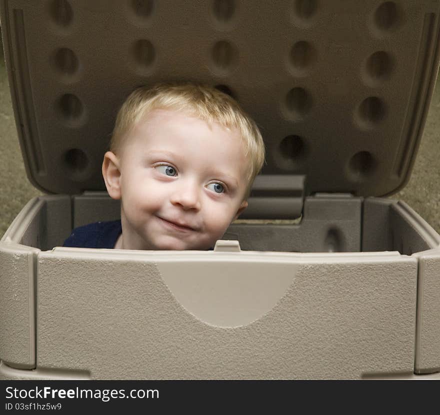 Little boy playing in a storage box with a cute expression on his face. Little boy playing in a storage box with a cute expression on his face