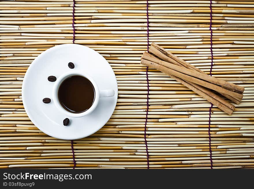 Coffee in cup and cinnamon on burlap of bamboo