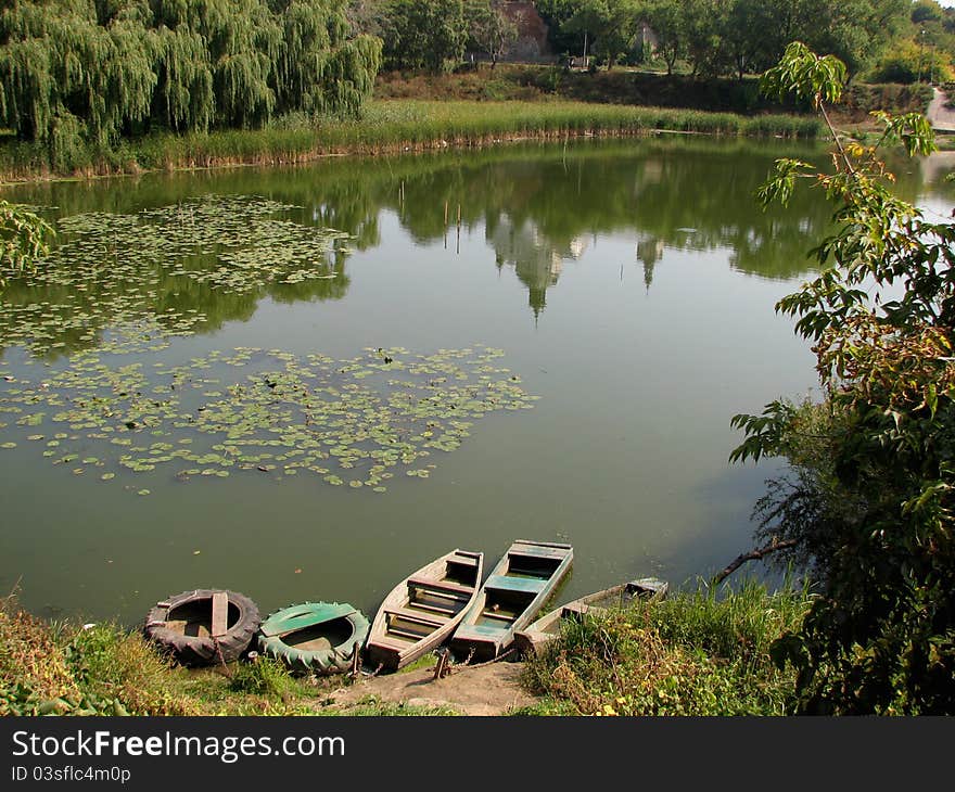 Reflection of the temple on the surface of the water. Near the lake's bank are wooden boats.