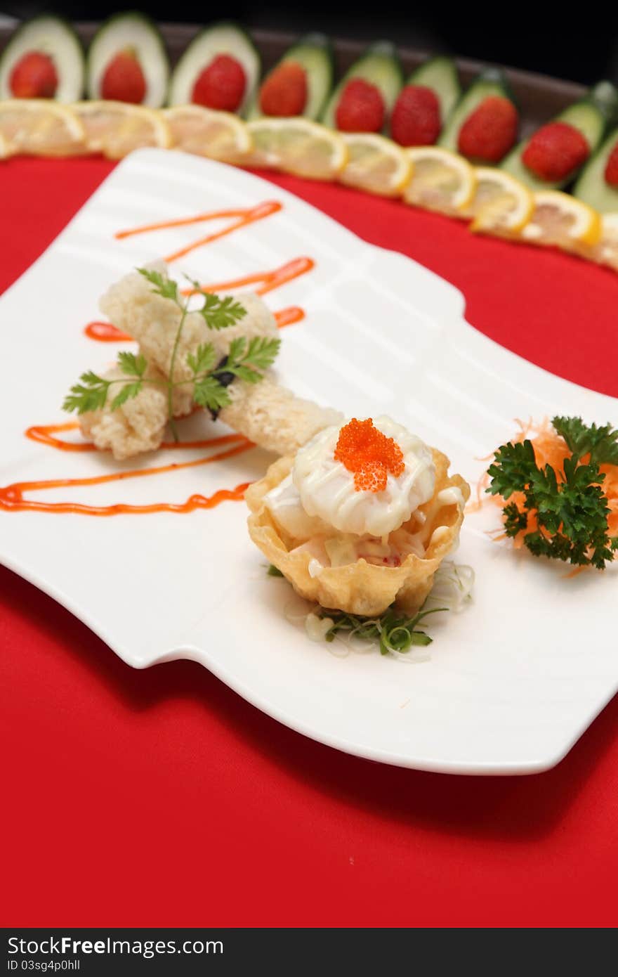 A plate of mixed Chinese delicacies, placed on a white plate and having also soup and sauces on the background.