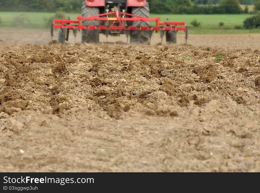 Plowed field in the foreground in front of a tractor in the distance. Plowed field in the foreground in front of a tractor in the distance