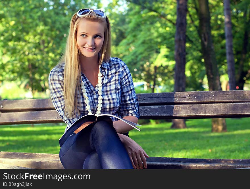 Young woman reading book in a park. Young woman reading book in a park