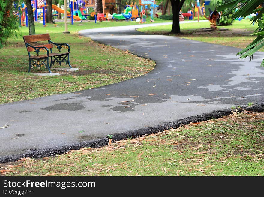 A walking path with a bench in the beautiful park. A walking path with a bench in the beautiful park