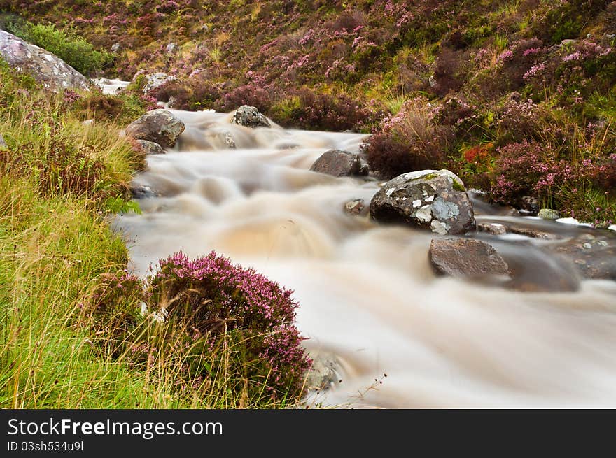 Quick flowing mountain stream through heather in Scotland. Quick flowing mountain stream through heather in Scotland