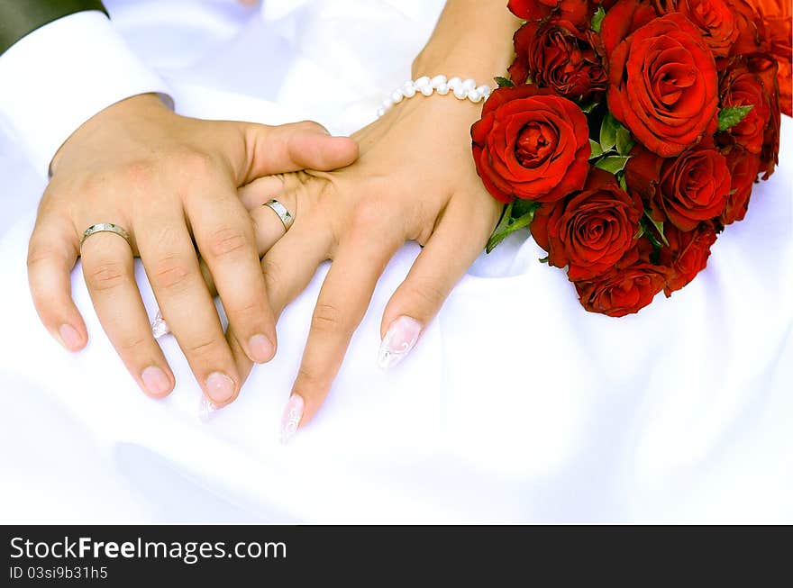 Bride and groom holding hands and a bouquet of red roses. Bride and groom holding hands and a bouquet of red roses