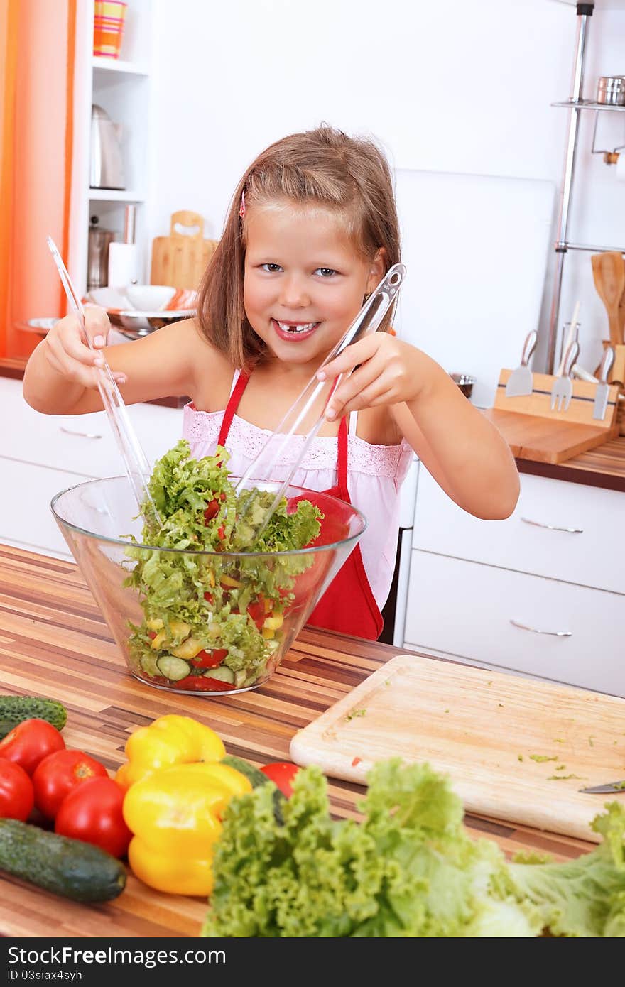 Smiling young girl making healthy salad in the kitchen. Smiling young girl making healthy salad in the kitchen